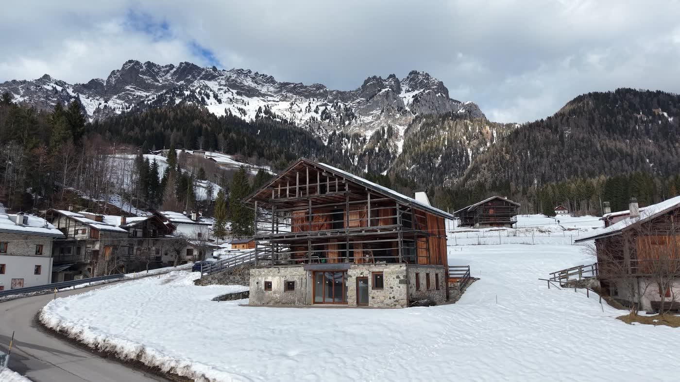 Chalet in legno tra la neve e le Dolomiti, ripresa con drone